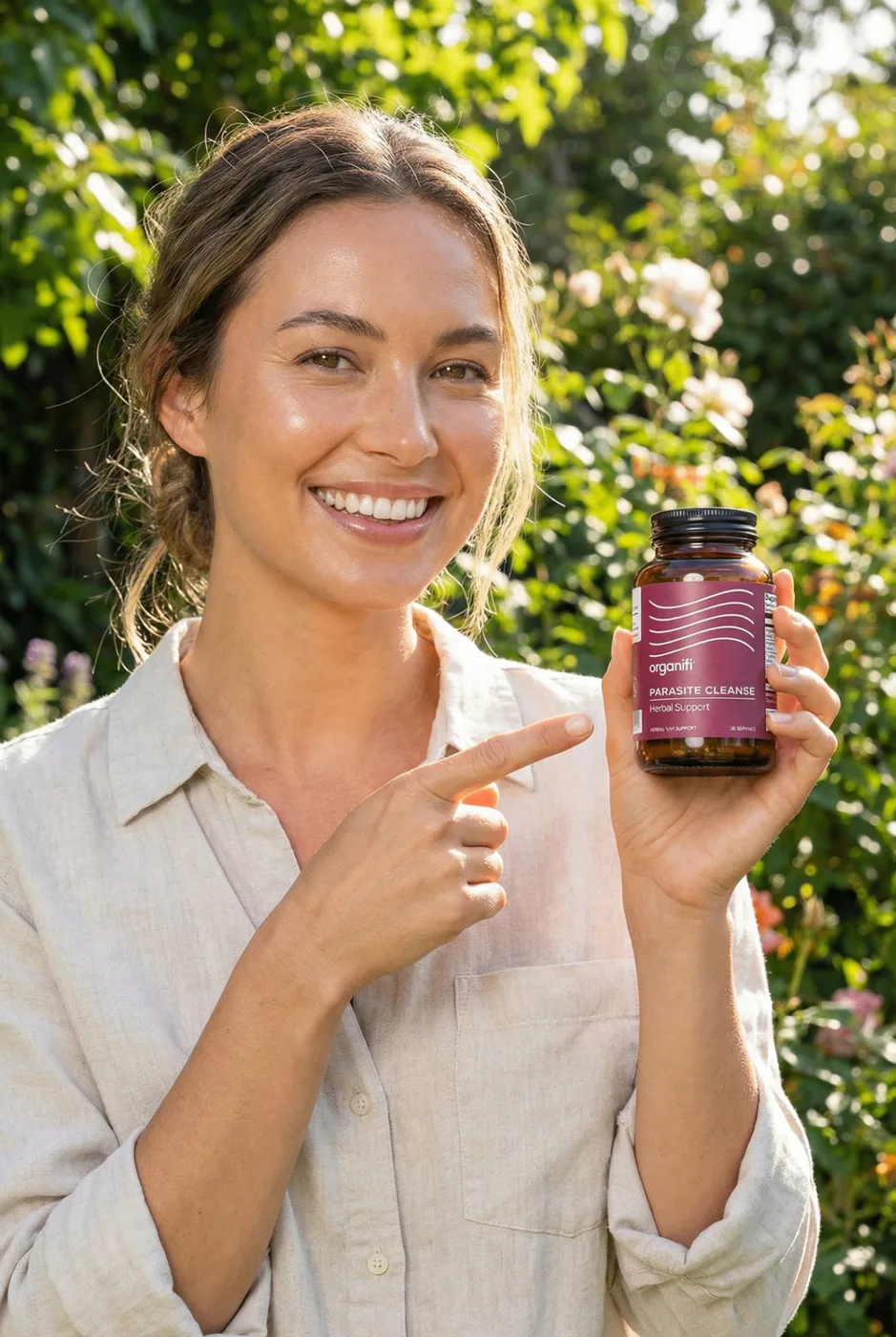 Smiling woman pointing at Organifi Parasite Cleanse bottle